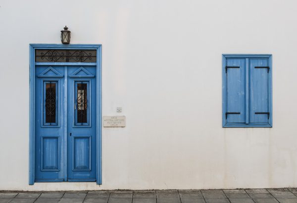 Pared blanca de una casa con puerta y ventana pintadas de azul