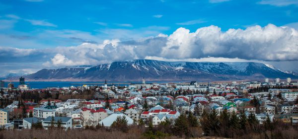Pequeña ciudad con abundantes casas blancas de tejados rojizos en Islandia y montaña nevada a lo lejos