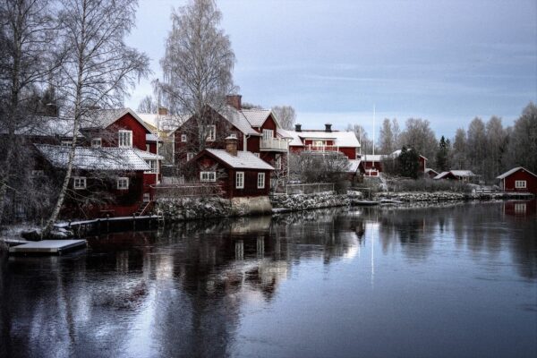 Pueblo de Suecia con río, árboles sin hojas, casas con nieve en los en los tejados y cielo despejado